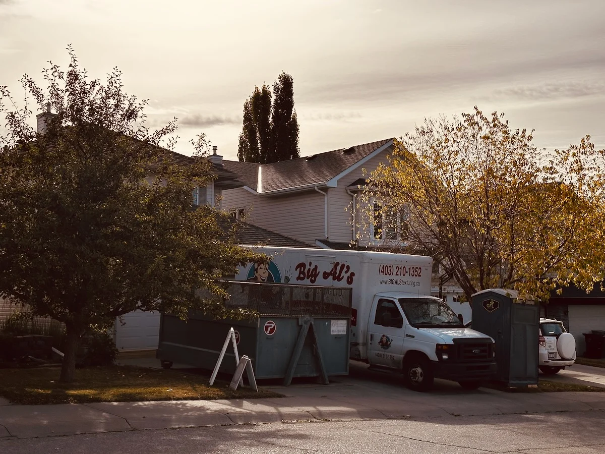 A residential house with a Big Al’s moving company van parked in front, surrounded by autumn foliage in the late afternoon light.